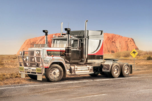Truck on a road with Uluru in the background